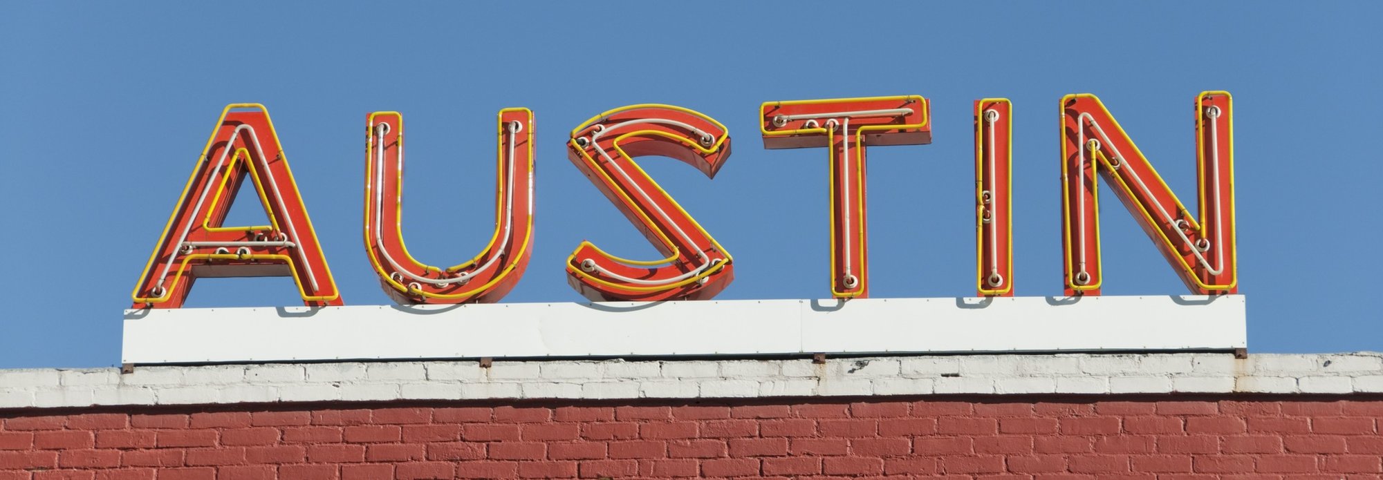photo of a brick building with block neon letters on the roof that read: AUSTIN